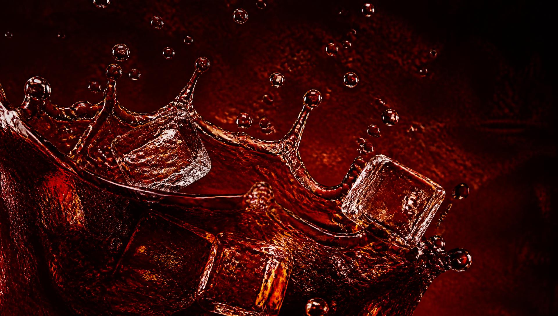 Cola splashing over ice cubes